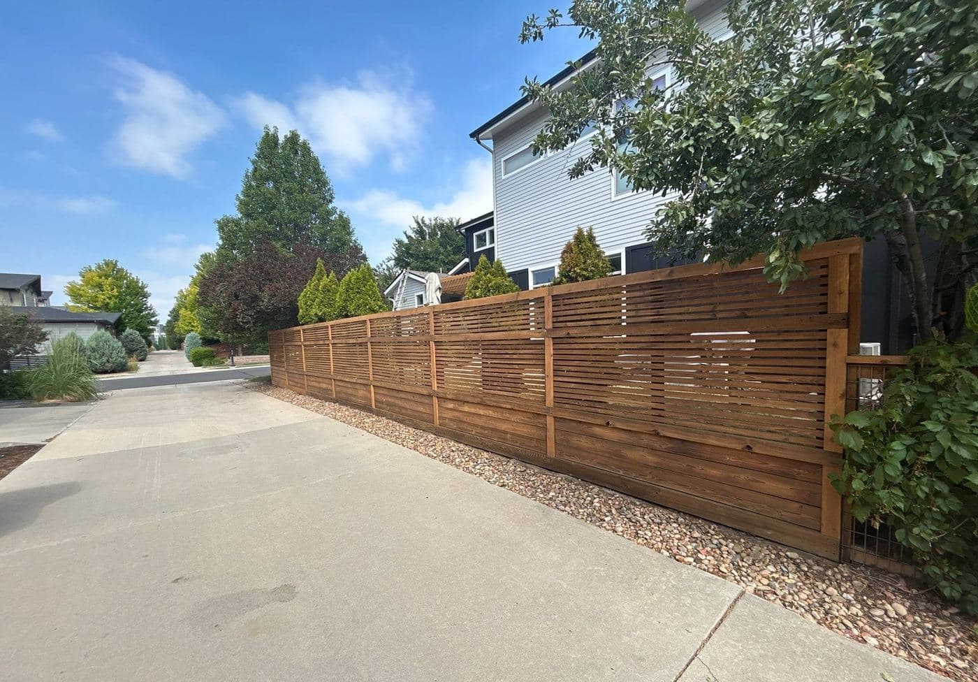 Horizontal slat fence stained a warm brown beside a driveway