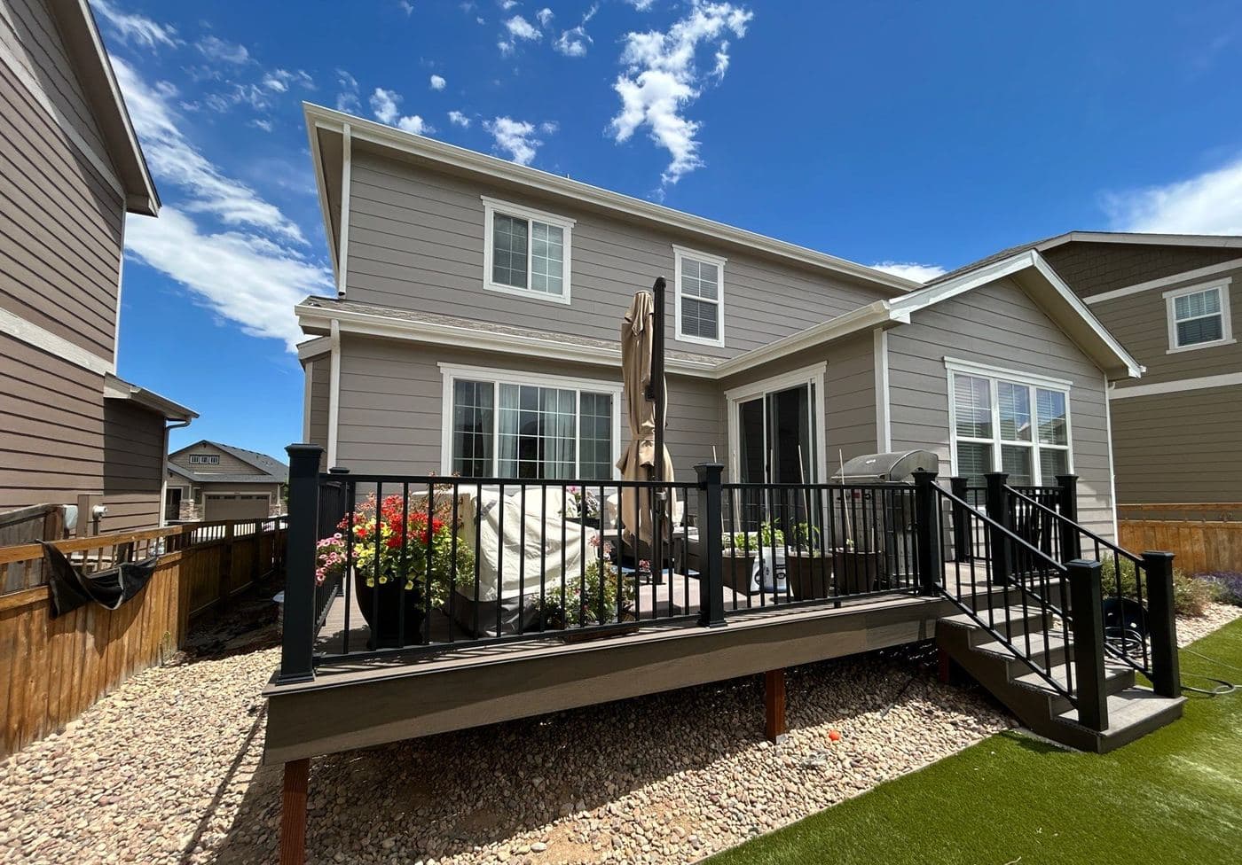 Tan home with white trim and a black railed front deck