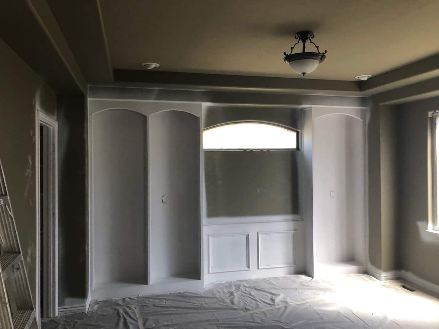 Arched built-in shelving primed gray against a dark wall