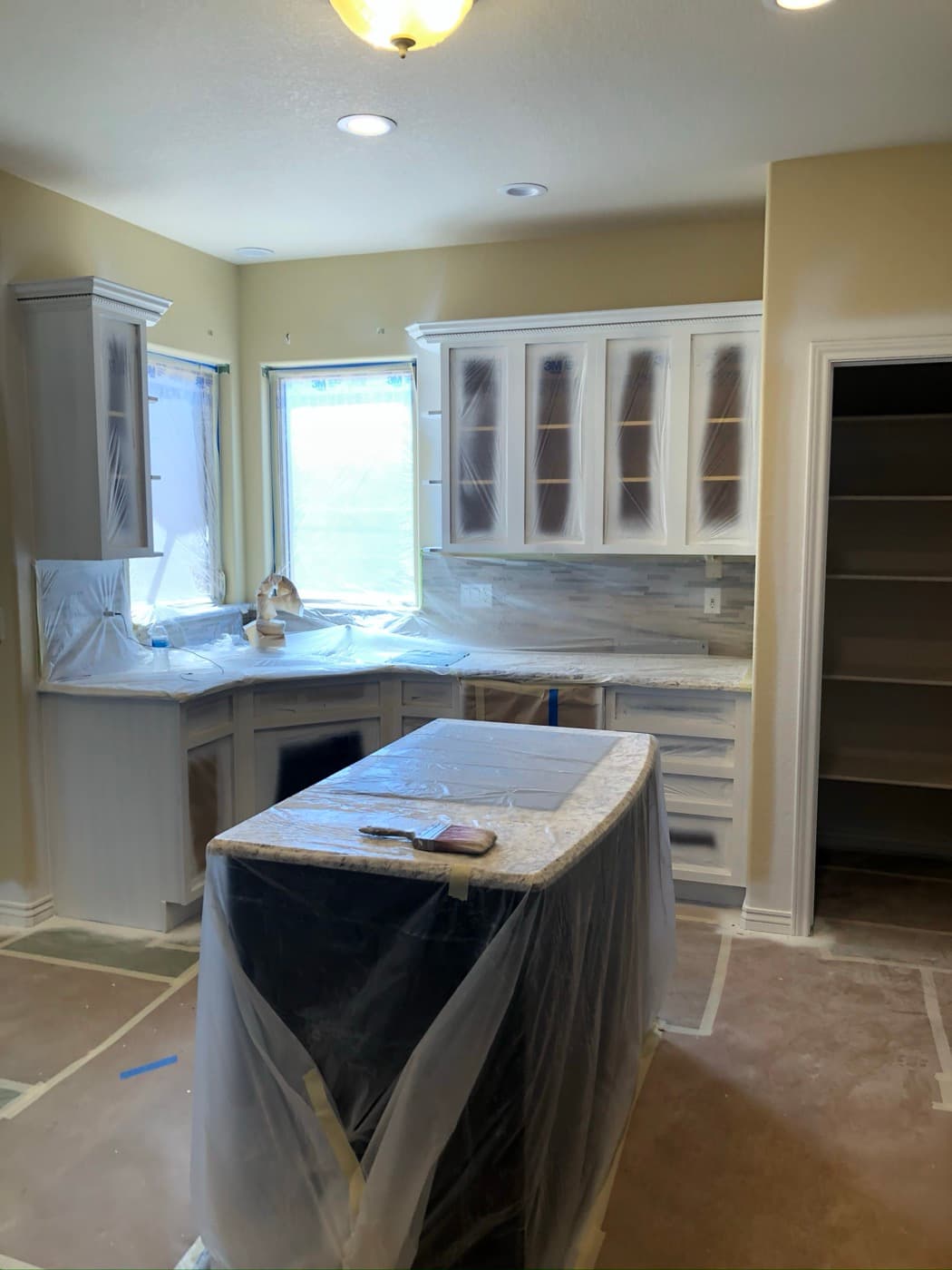 Bay-window kitchen sprayed white with the worktops still masked