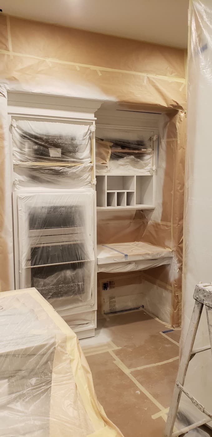 Built-in desk and pantry cabinetry masked off mid-respray