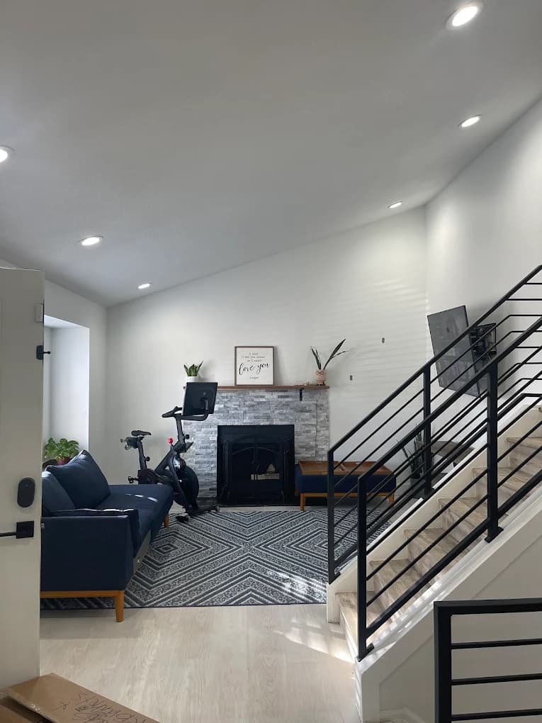Living room with a black staircase, white walls and a wood floor