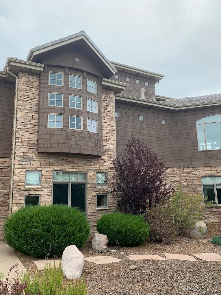 Stone and siding home with fresh trim and landscaped beds