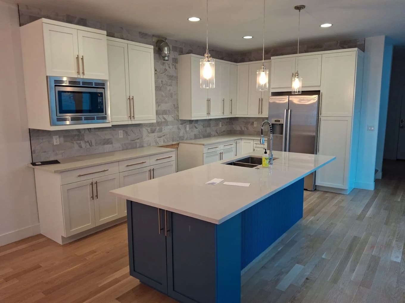 White kitchen with a navy island and stone worktop