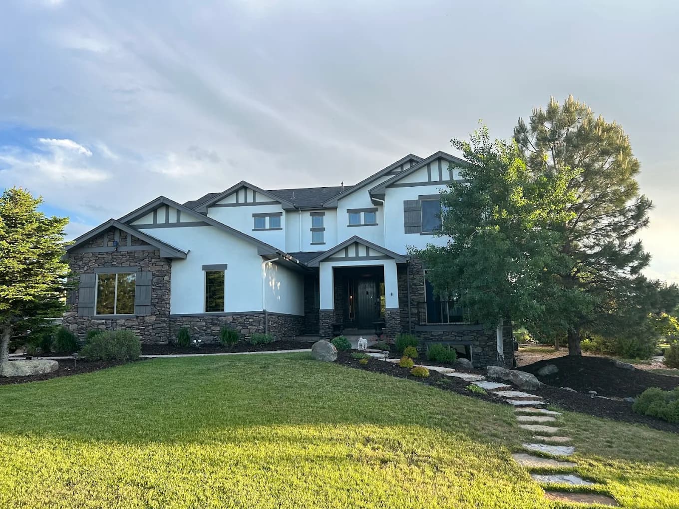 Gray craftsman home with a stone path and porch columns