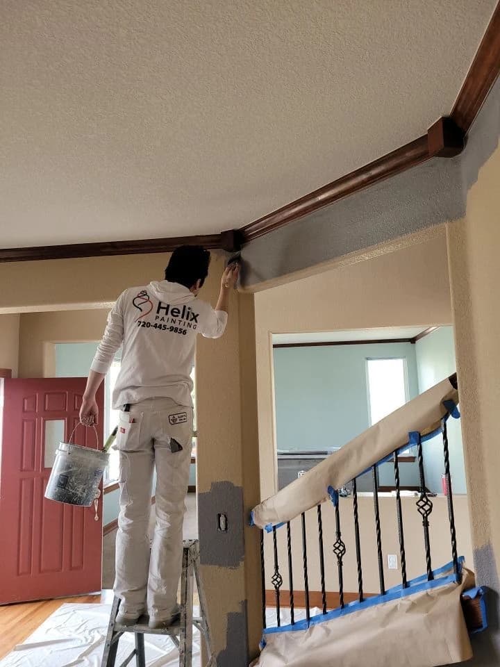 Painter on a ladder cutting in above a stairwell