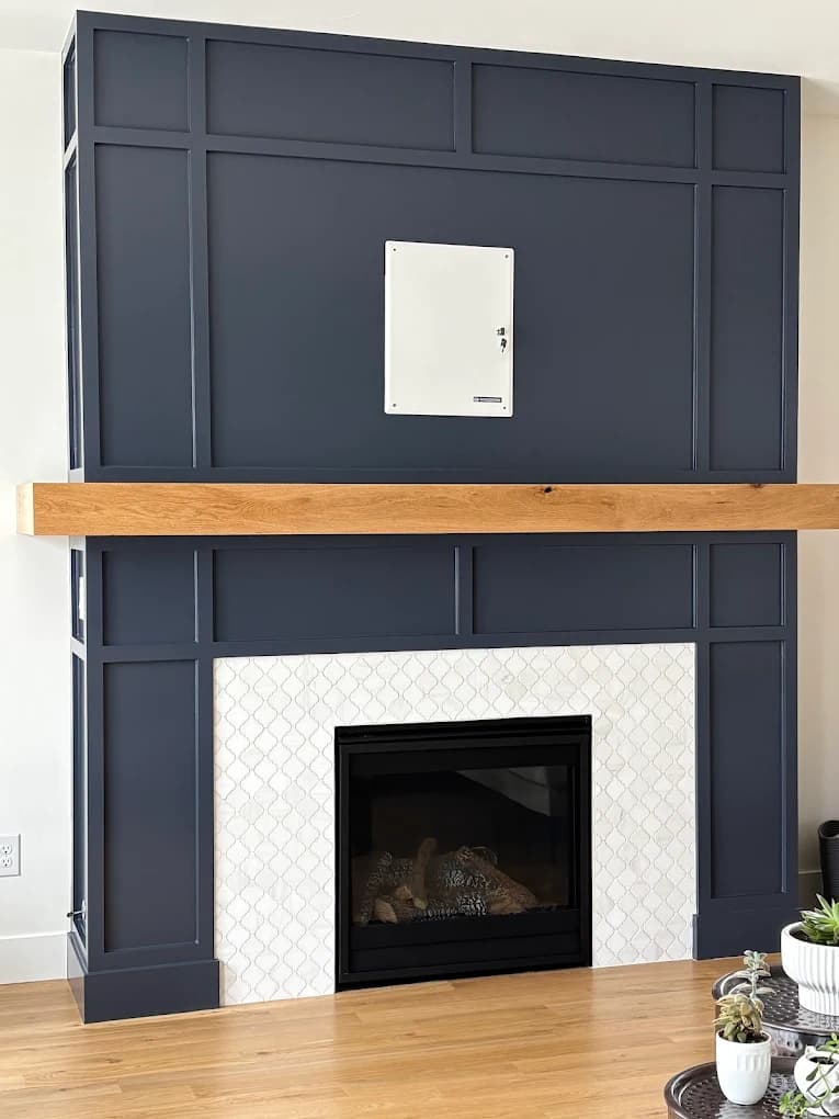 Fireplace wall panelled and painted in deep navy with a timber mantel