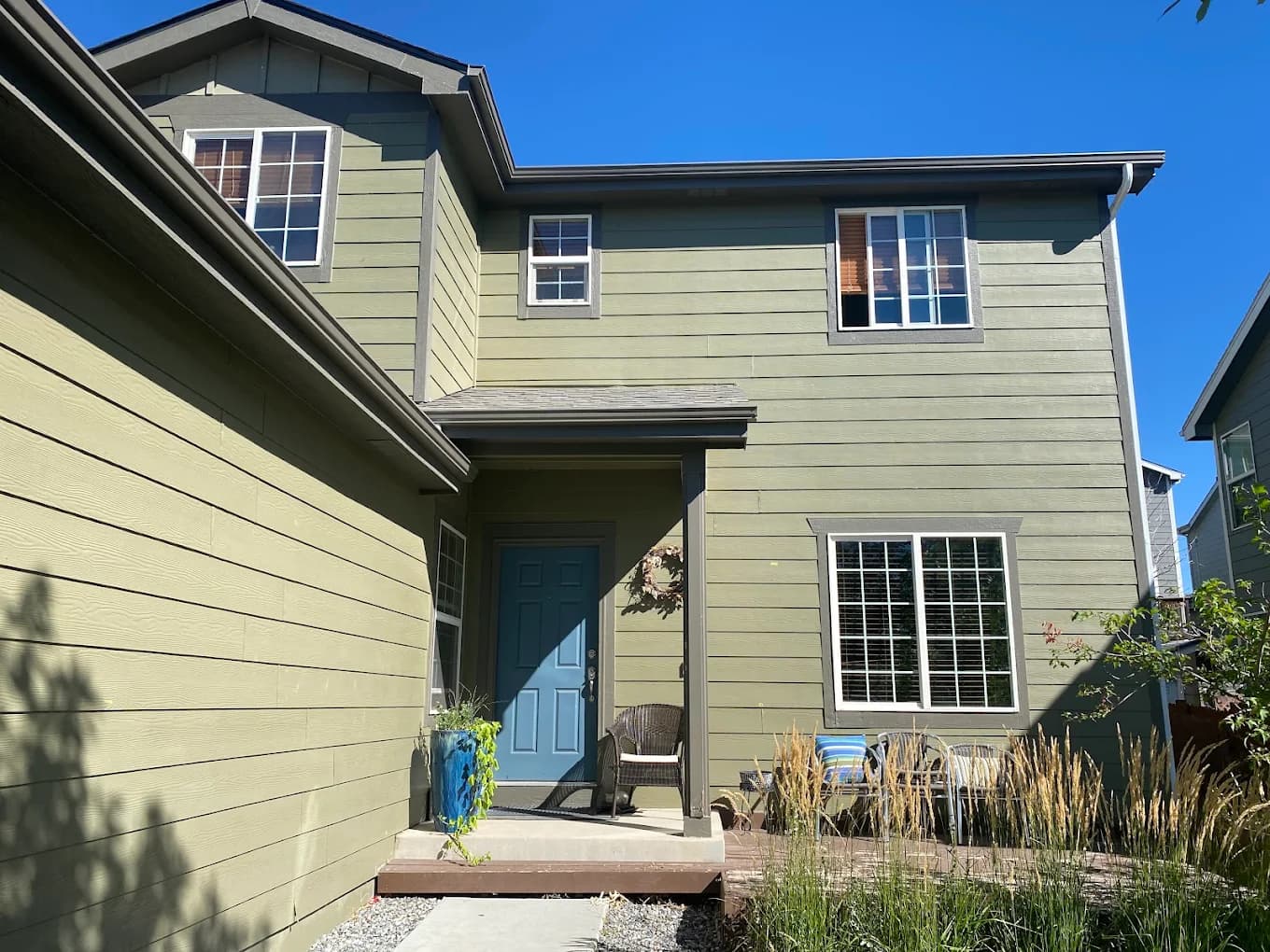 Green-gray two-storey siding with white window trim