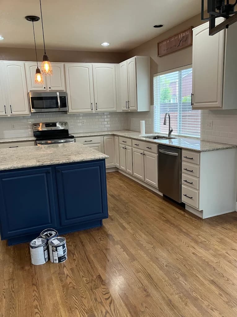White kitchen with a navy island and pendant lights
