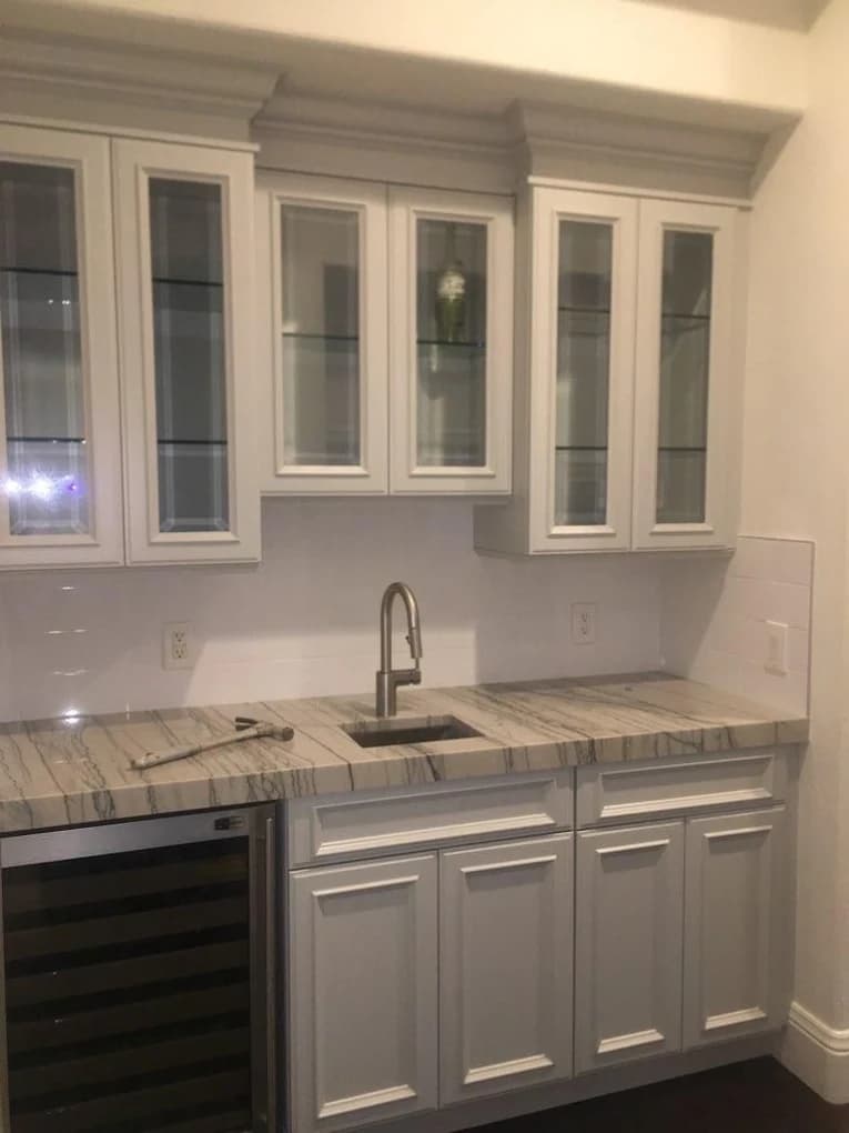 Cream bar cabinetry with a wine fridge and stone counter
