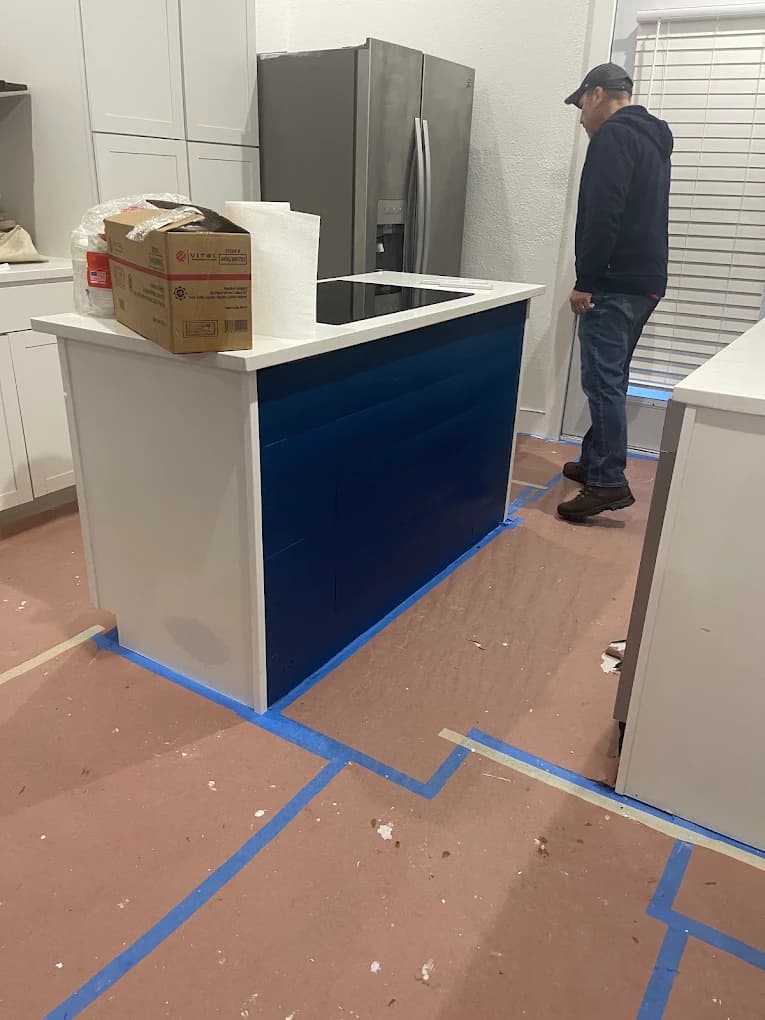 Painter finishing a navy kitchen island