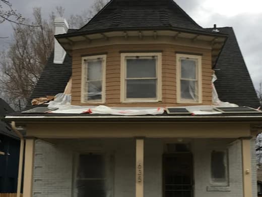 Victorian house with peeling tan siding and masked windows