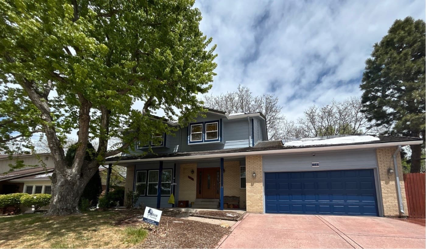 Two-storey home repainted slate blue with a navy garage door and a Helix sign in the yard