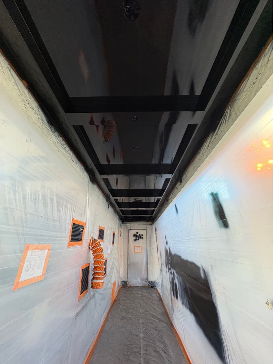 Commercial corridor sealed under containment with the ceiling sprayed black