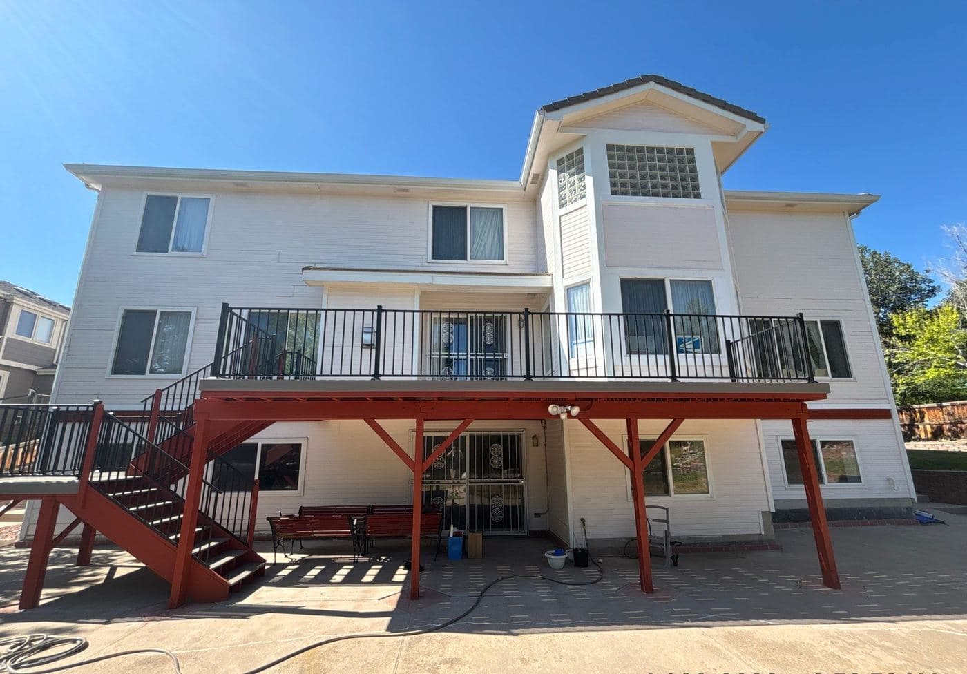 White home with a maroon painted deck frame and stairs