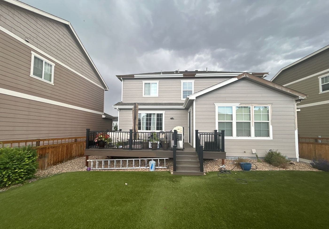 Raised rear deck with black railings above an artificial lawn
