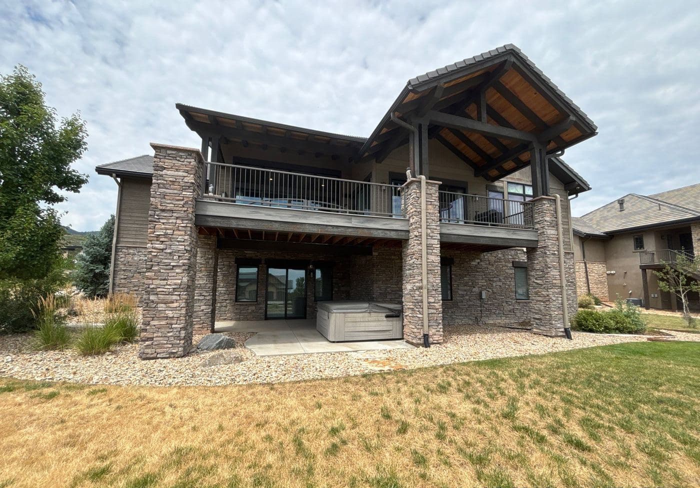 Mountain-style home with stone, timber and a covered balcony
