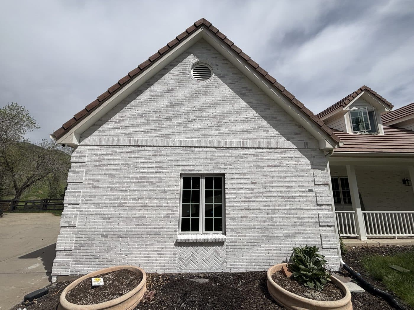 Brick home painted white, with a dark-framed window below the gable
